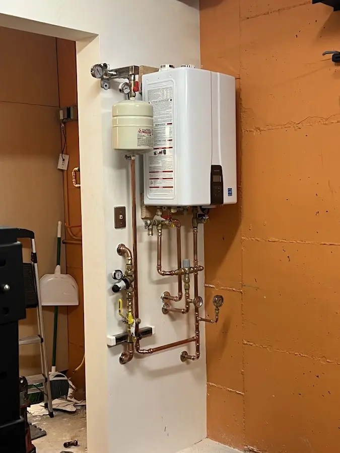 Plumbing technician inspecting water heater connections in Muskegon